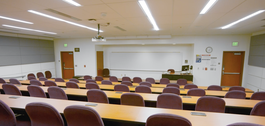 Main Lecture Hall on the lower level from the back of the room facing the screen and front desk.